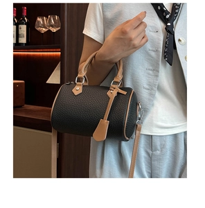 Close-up of black lychee grain leather Boston bag with brown handles and shoulder strap