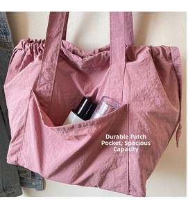 Detail of pink nylon tote bag showing a functional side pocket with skincare bottles