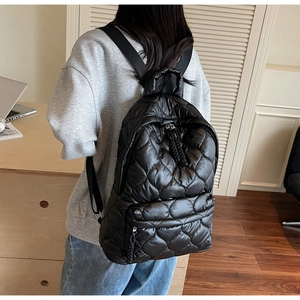 Close-up of quilted wave pattern and woven zipper pull on a black padded backpack
