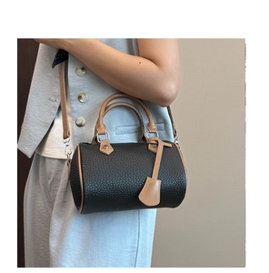 Detail of black lychee grain leather Boston bag with contrast handles and slim shoulder strap