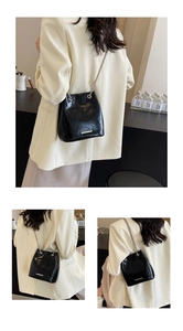 Detail of black glossy bucket bag with silver chain strap and metal trim decor
