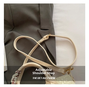 Detail view of adjustable shoulder strap on cream woven bucket bag with gold hardware