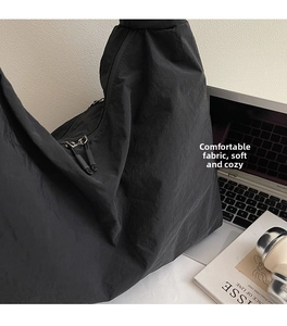 Detail of black canvas tote bag with dual silver zippers and soft wrinkled texture fabric