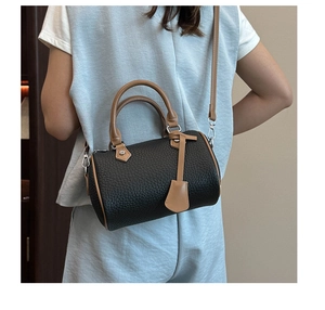 Detail of a two-tone Boston bag showing lychee grain texture and brown leather straps