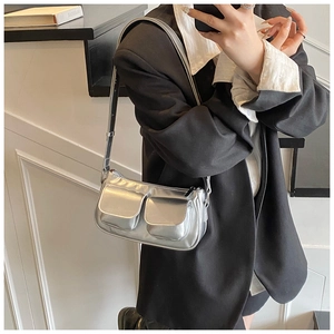 Detail of silver metallic shoulder bag with dual front flap pockets and adjustable strap