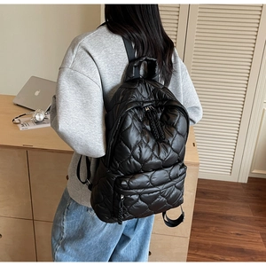 Side view of a black quilted backpack on a model showing large capacity and rhombic texture