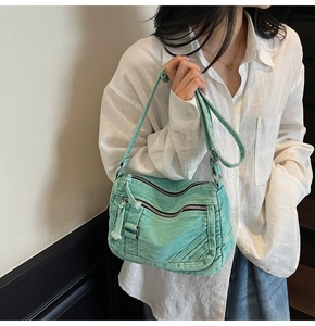 Detail view of mint green denim crossbody bag with multi-zip pockets and adjustable strap