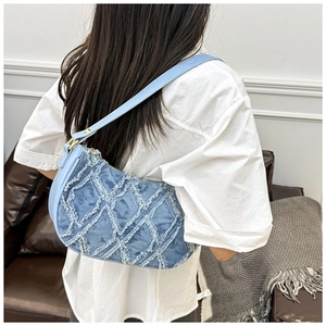Detail of denim underarm bag with frayed edge lattice pattern worn by model