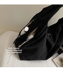 Detail of the side zipper pocket on a black canvas tote bag for storing small essentials