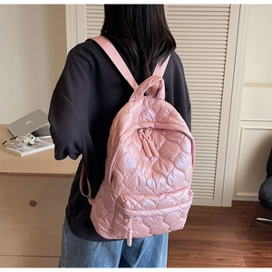 Detail of pink heart-quilted backpack showing silk-like nylon texture and zipper details