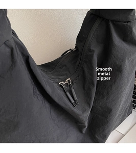 Close-up of smooth dual metal zippers and durable pull cords on black canvas tote bag