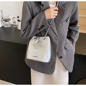 Detail view of a silver bucket bag with chain strap styled in a modern cafe setting
