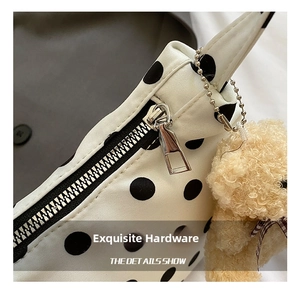 Detail of silver zipper closure and plush bear charm on white polka dot tote bag