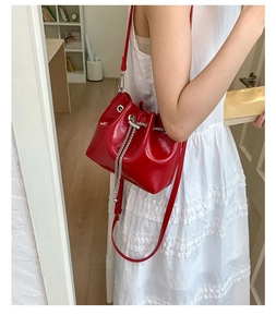 Détail du sac seau rouge montrant la texture brillante et le cordon en chaîne argentée