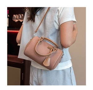 Detail of light brown lychee leather Boston bag featuring dual handles and a strap