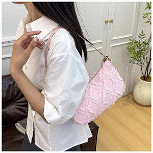 Detailed close-up of a pink denim underarm bag featuring frayed diamond quilt textures