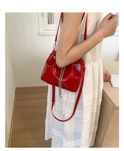 Gros plan sur le sac seau rouge vif avec chaîne argentée et finition vernie brillante