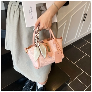 Close-up of pink woven bucket bag with silk scarf handle and golden metal twist lock
