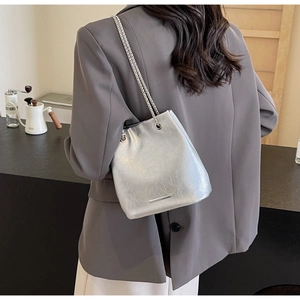 Detail of silver crinkled leather bucket bag with metallic chain and modern design