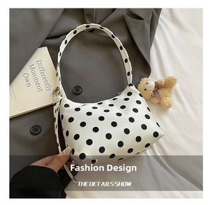 Detailed view of polka dot pattern shoulder bag with adjustable silver buckle