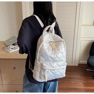 Detail view of pearl white quilted backpack with rhombic stitching on a model's back