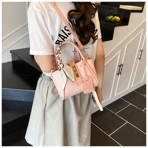 Détail du sac à main tressé rose avec foulard en soie et fermoir doré sur escalier
