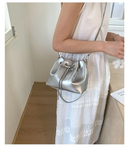 Détail d'un sac seau argenté métallisé avec bandoulière chaîne porté par un modèle