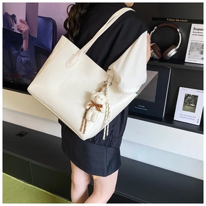 Détail du sac cabas blanc à motif crocodile avec charm ours et pompon tressé