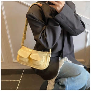 Detail showing a light yellow glossy leather shoulder bag with two front pockets on a model