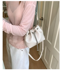 Détail du sac seau en cuir blanc montrant le cordon en chaîne et la texture lisse