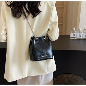 Detail of black large bucket bag with silver chain and pleated texture on smooth leather