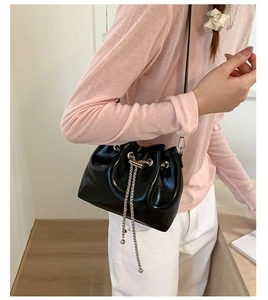Detailed view of black drawstring bucket bag with silver chain and sphere pendant