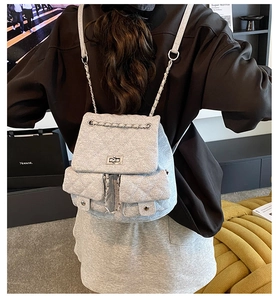 Detail of tweed denim backpack featuring quilted pattern and silver metal chain strap