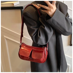 Detail of red glossy patent leather shoulder bag featuring unique double front pockets