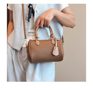 Detail of brown pebbled leather Boston bag showing silver hardware and crossbody strap