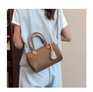Brown litchi grain leather Boston bag worn crossbody to show size and scale