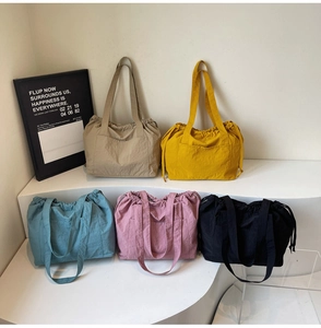Detail view of five nylon tote bags with drawstring closure and front pockets in various colors