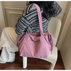 Detail of pink nylon tote bag showing crinkled fabric texture and large front pocket