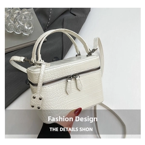 Detail of white crocodile pattern handbag with dual zipper closure and top handle