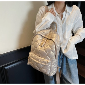 Detailed view of champagne gold quilted backpack with bubble texture and woven zipper pull