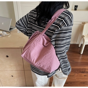 Detail of pink nylon tote bag with drawstring closure and front pockets for daily commute