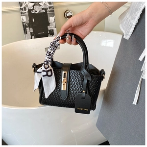 Détail du sac à main tissé noir avec fermoir doré rotatif et écharpe pied-de-poule
