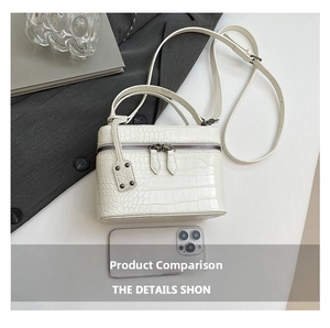 Detail of off-white crocodile embossed mini box bag with top handle and smartphone for scale