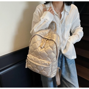 Close-up of champagne gold quilted backpack featuring metallic gloss and detailed front pocket