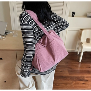 Detail of a pink nylon tote bag with side pocket shown in a lifestyle office setting