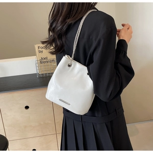 Detail of white leather bucket bag with silver chain straps worn with black dress