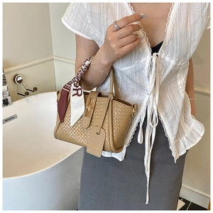 Detail of camel woven leather bucket bag with gold lock and decorative silk scarf
