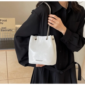 Detail of glossy white bucket bag with elegant silver chain strap and metal accent
