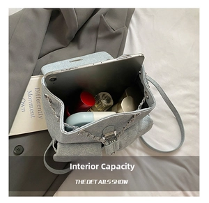 Detailed interior of a quilted blue denim backpack with silver chain and daily essentials