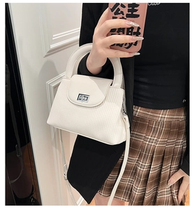 Detail of white textured leather handbag with silver clasp and slim shoulder strap
